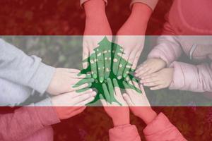 Hands of kids on background of Lebanon flag. Lebanese patriotism and unity concept. photo