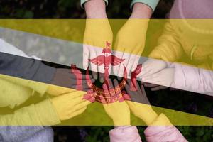 Hands of kids on background of Brunei flag. Bruneian patriotism and unity concept. photo