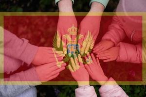 Hands of kids on background of Montenegro flag. Montenegrin patriotism and unity concept. photo