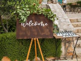 Plaque with inscription greeting guests at wedding. Welcome inscription sign wedding decorations. Wedding decor outdoor marriage photo