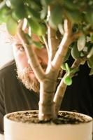 Male eye emerging behind potted plant and man hiding - spying and shadowing concept photo