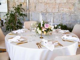 Wedding banquet concept. Chairs and round table for guests, served with cutler and, flowers and crockery and covered with a tablecloth photo