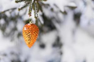 Ornament fir tree cone Christmas tree decoration toy hanging on spruce branch with snow branches on background. Copy space. Close-up. photo