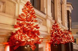 Red Christmas trees sparkler garland decoration of street. Beautiful winter holidays scenery in city. New year xmas card - creative christmas decoration photo