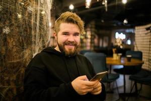 Portrait happy guy making money transaction via application on mobile phone with 4g internet sitting at cafe in street evening, serious millennial man reading text message on smartphone photo