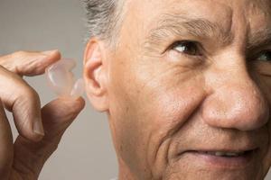 Older Man using custom made silicone earplugs for hearing protection photo