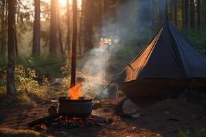 A tent in the forest in the summer by a fire with a pot from which steam comes from food. . photo