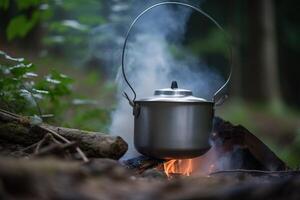 A camping kettle hangs over a fire in the forest in summer. Active holidays on vacation. . photo