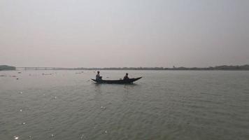 Dhaka, Bangladesh - April 18, 2023, Beautiful scenery of a wooden boat floating on the river. A sailor sailing a boat on the river. Beautiful rural life and scenic view of a river and the river water video