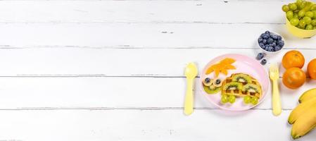 Creative idea for kids breakfast - waffle kiwi banana orange turtle shape, cute and funny kids food. Banner with space for text photo