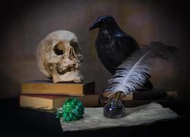 Books a human skull, a raven and a green carnation. photo