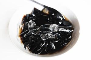 Thai Sweet dessert grass jelly with Ice in white bowl. A kind of Chinese vegetable is black jelly or Herbs can relieve heat in human body system and Aphthous stomatitis in summertime. photo