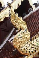 Golden naga on Art Roof of Buddhist temple with blue sky in Thailand photo