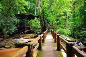 Beautiful wood house and bridge in greenery jungle.Tourists enjoy in the waterfall and stream on the rock of tropical rainforest in national park at Thailand photo