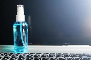 A clear bottle Ethanol or ethyl alcohol spray for based hand rub is highly effective in reducing influenza a virus on human hands on laptop. Healthy and Covid-19 virus epidemic Concept. photo