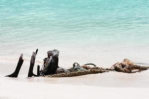 antiguo madera y cuerda en el playa y blanco arena con azul mar en luz de sol foto