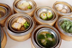 Traditional steamed chinese food Dim Sum and dumplings served preparation in bamboo basket photo