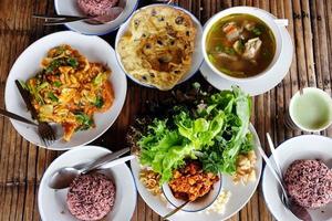 Traditional and culture Thai food Rice, pork omelette with Puff Ball Mushrooms, Smoked shrimp chili dip with vegetables, Pork spare rib Spicy soup and Stire Fried Sukiyaki with chicken on wood table photo