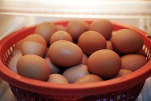 Fresh chicken eggs on red plastic basket in refrigerator. The benefits of eating eggs are high protein. photo