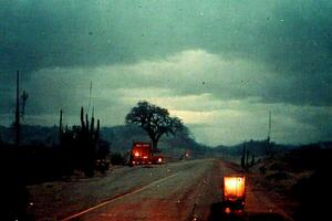 truck driving down a road under a cloudy sky. . photo