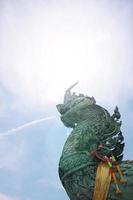 estatua de verde naga Phaya nak es escupiendo agua con luz de sol a samila playa en Tailandia foto