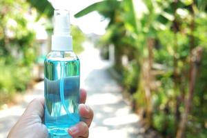Hand holding a bottle of Ethanol or ethyl alcohol spray for based hand rub is highly effective in reducing influenza a virus on human hands in natural garden. Healthy and Covid19 epidemic Concept. photo
