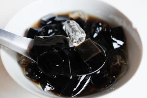 Thai Sweet dessert grass jelly with Ice in white bowl. A kind of Chinese vegetable is black jelly or Herbs can relieve heat in human body system and Aphthous stomatitis in summertime. photo