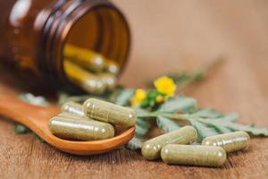 Herbal medicine capsules spilling out of a bottle ,soft focus. photo