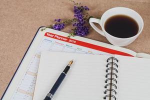 personal organizer or planner with fountain pen and hot coffee on wood table. photo