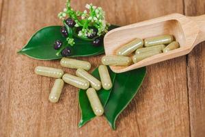 Herbal medicine capsules from herb on rustic wooden table for healthy eating and good life ,soft focus. photo