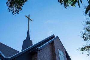 cross on top of roof with a blue sky. photo