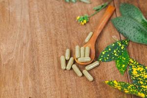 Herbal medicine capsules from herb on rustic wooden table for healthy eating and good life ,soft focus. photo