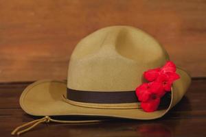 anzac Ejército flexible sombrero con rojo flor en Clásico madera antecedentes . foto