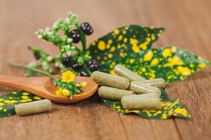 Herbal medicine capsules from herb on rustic wooden table for healthy eating and good life ,soft focus. photo