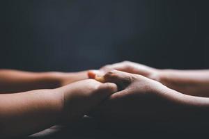 Christian family praying together concept. Child and mother worship God in home. Woman and boy hands praying to god with the bible begging for forgiveness and believe in goodness. photo