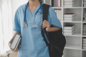 concepto médico y de salud. médico de medicina con estetoscopio en la mano y los pacientes vienen al fondo del hospital. foto