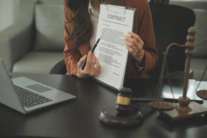 Justice and Law concept. Legal counsel presents to the client a signed contract with gavel and legal law or legal having team meeting at law firm in background photo