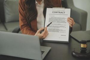 Justice and Law concept. Legal counsel presents to the client a signed contract with gavel and legal law or legal having team meeting at law firm in background photo