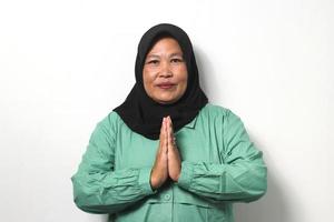 Smiling Middle aged Asian women wearing hijab gesturing Eid mubarak over white background. photo