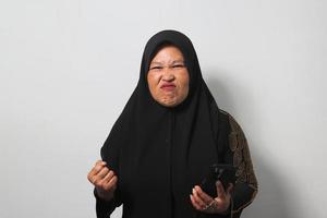 Middle aged Asian women wearing hijab feels upset while getting bad news on her phone photo