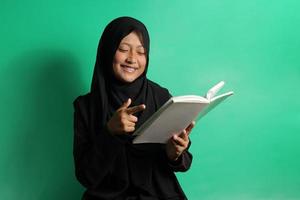 Cheerful young Asian girl pointing fingers on book photo