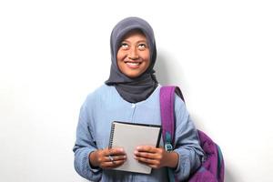 Young Asian girl student wearing hijab and backpack, looking up isolated on white background. photo