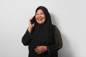 Happy Middle aged Asian women wearing hijab talking on mobile phone and laughing photo