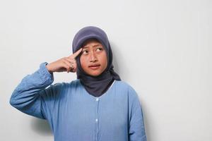 Thoughtful young Asian girl in hijab is thinking with smiling face photo