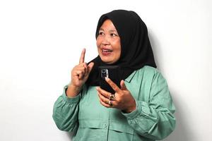 Cheerful Middle aged Asian women wearing hijab pointing finger up got an idea photo