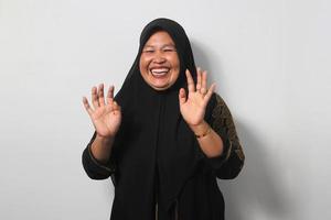 Funny Middle aged Asian women wearing hijab laughing hard with big open mouth photo