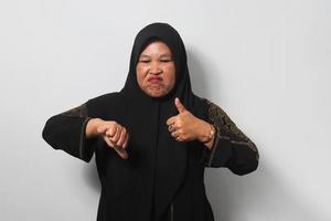 Upset Middle aged Asian women wearing hijab show thumbs down gesture, give negative opinion, judging bad photo