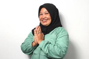 sonriente medio Envejecido asiático mujer vistiendo hijab gesticulando eid Mubarak terminado blanco antecedentes. foto