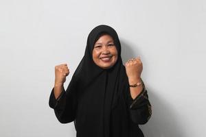 Strong Middle aged Asian women wearing hijab raises arms and looking at camera photo