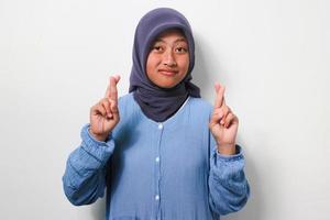 Young Asian girl in hijab holding fingers crossed photo